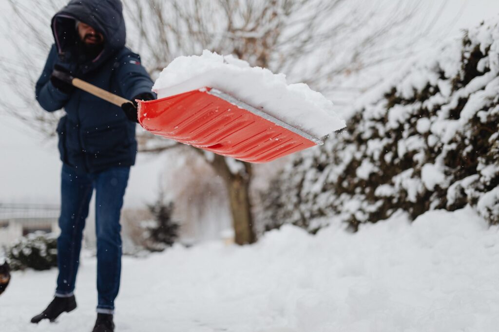Ein geräumter Gehweg im Winter bei Schneefall